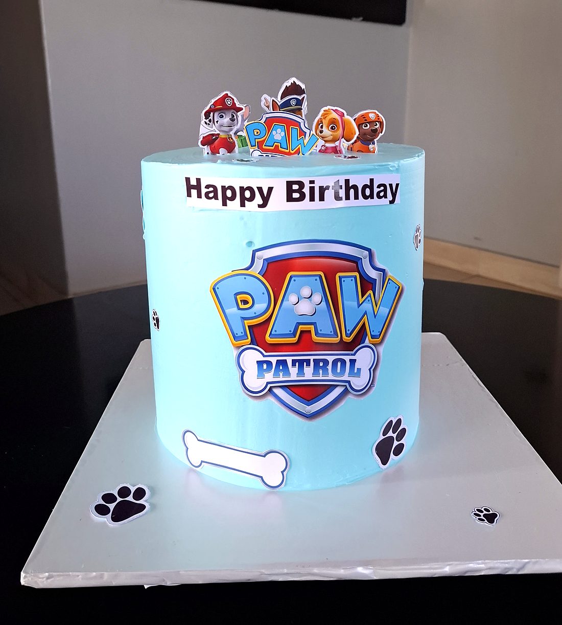 Light blue Paw Patrol birthday cake with character toppers and paw prints