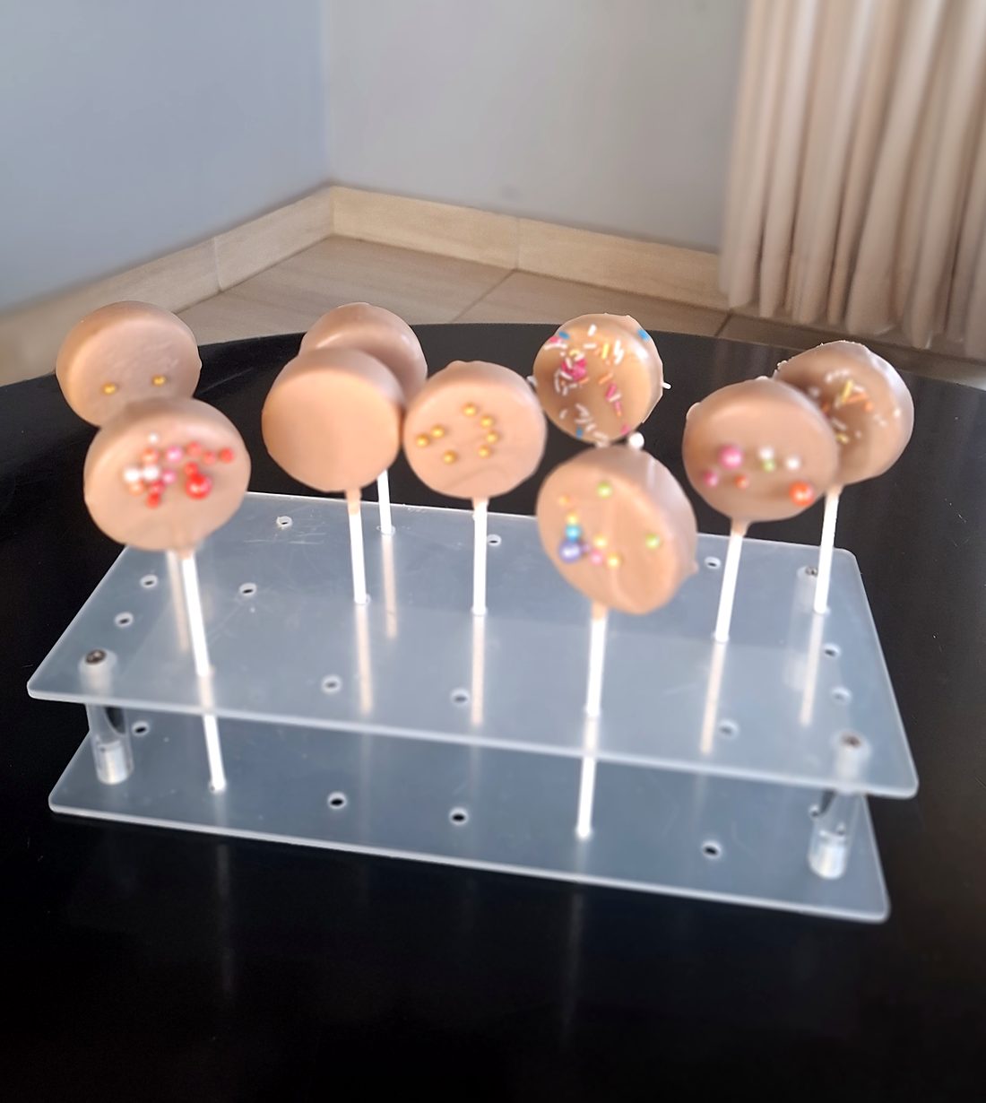 Caramel cake pops with colourful sprinkles on a clear stand